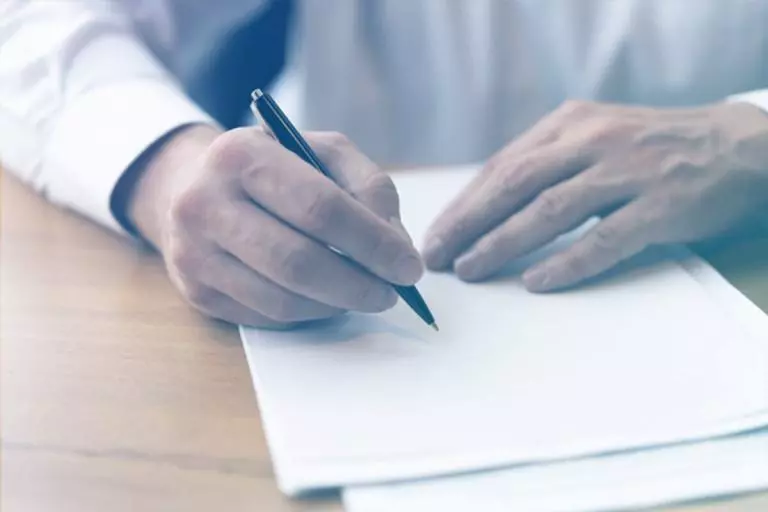 Homem segurando caneta prestes a assinar documento