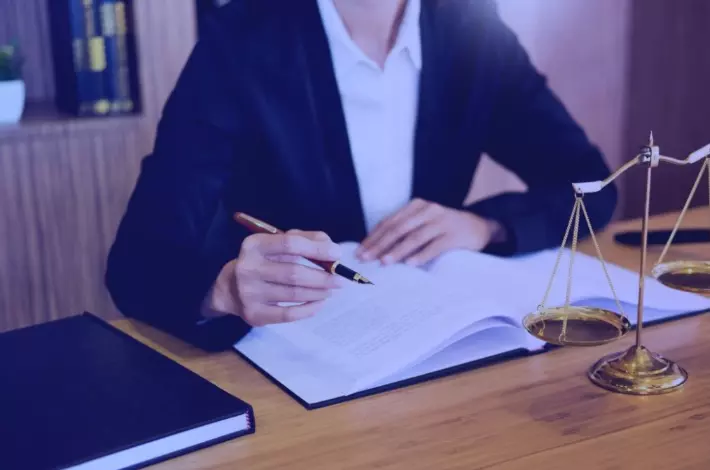 advogada segurando caneta com livro sobre a mesa