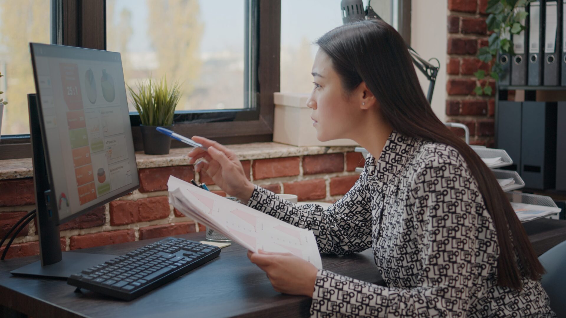 mulher asiática analisando informações na tela de um computador, por meio do qual ela faz a gestão do contencioso