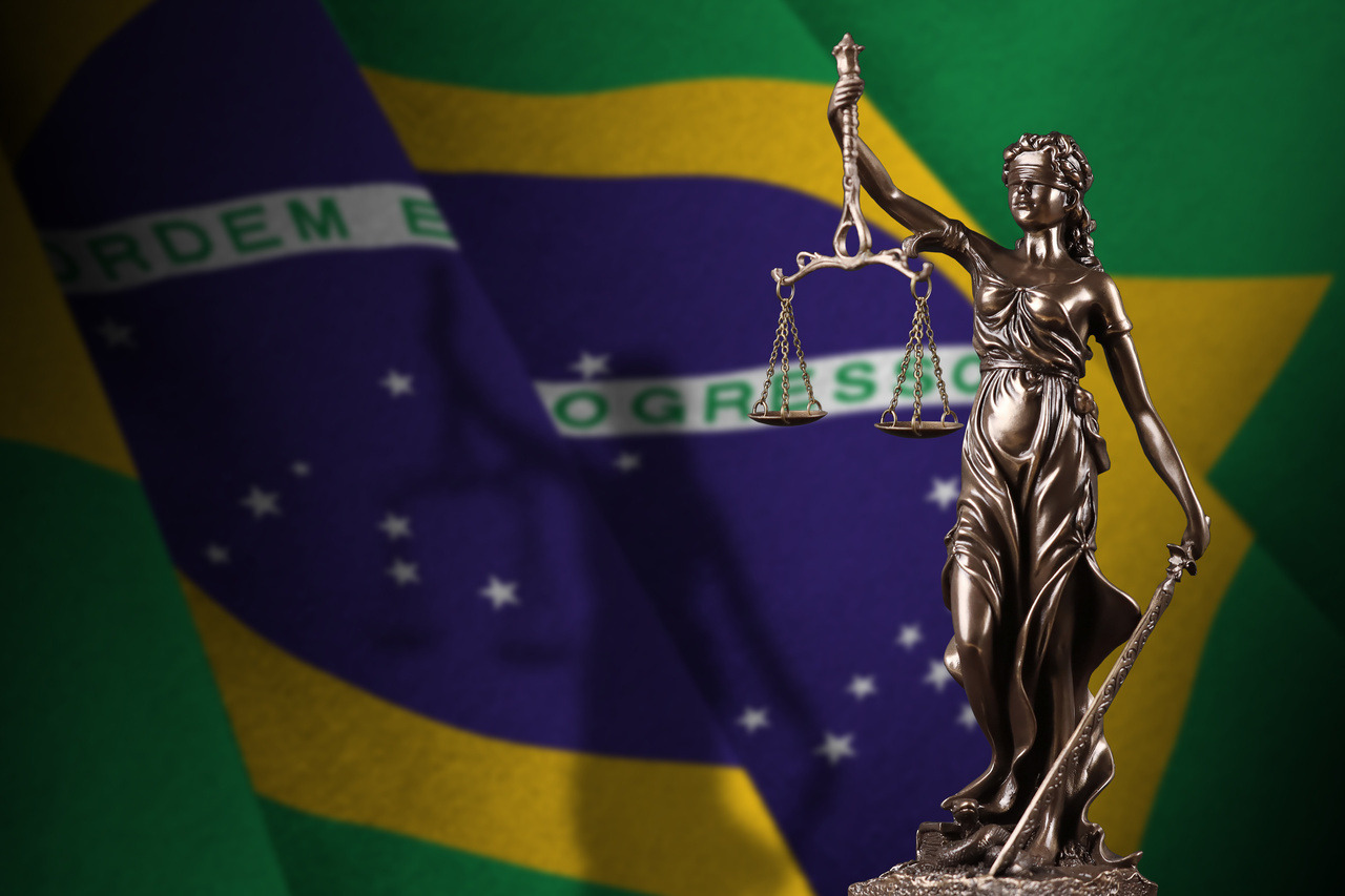 Bandeira do Brasil ao fundo com estátua da justiça à frente representanto a Constituição Federal de 1988